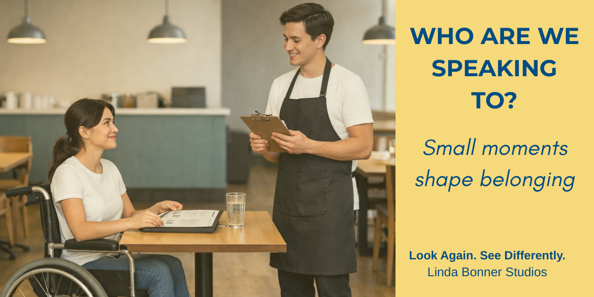 “A restaurant server taking an order at a table, speaking with a guest who is a wheelchair user during a casual dining moment.”